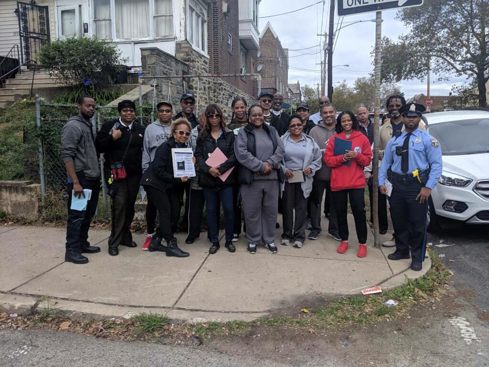A large group of people standing together on a street corer